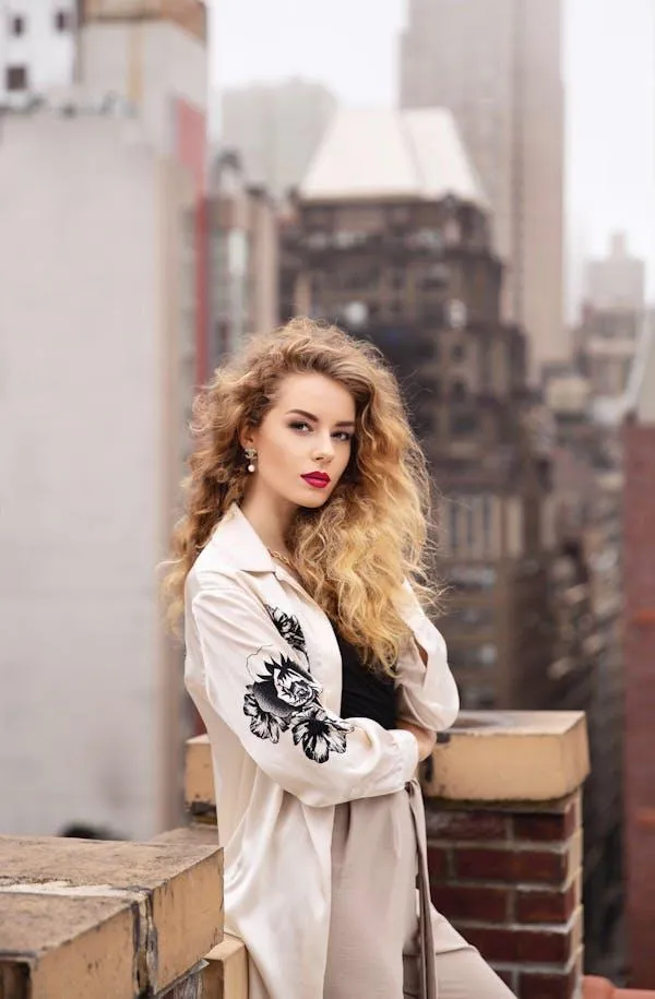 Woman with Curly Hair Posing on a City Balcony in a Jacket