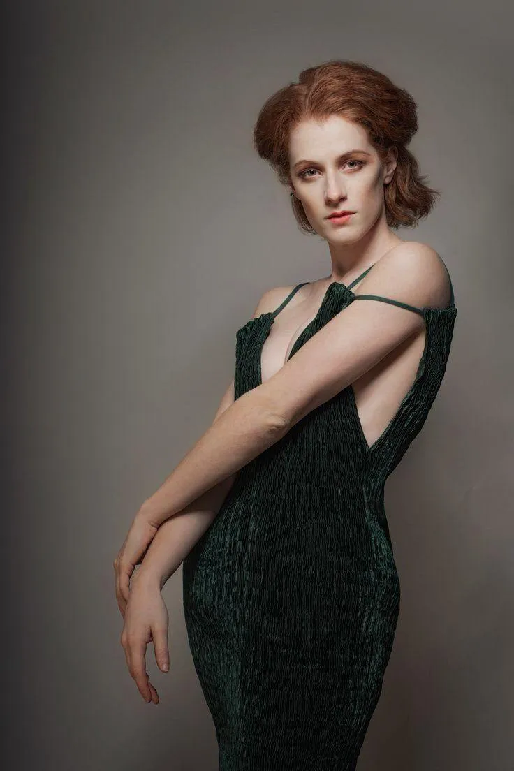 Woman in a Dark Green Dress Standing with Arm Across Chest
