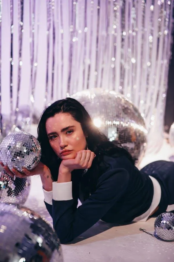 Woman in a Dark Outfit Posing with a Silver Disco Ball Props