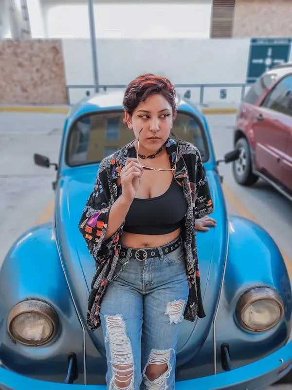 Woman in Denim Outfit Posing Confidently Next To a Blue Car