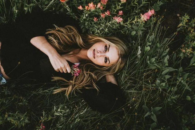 Woman in a Denim Shorts Sitting on Logs in a Sunny Field