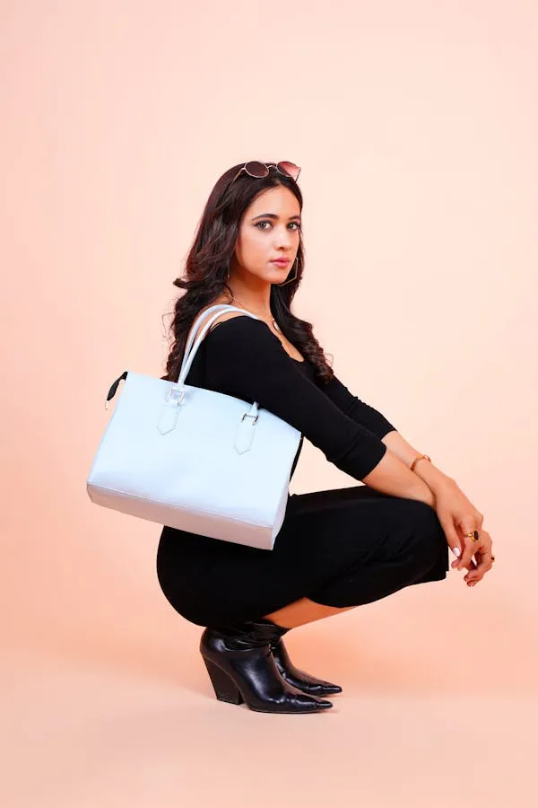 Woman Dressed in Black Holding White Handbag Posing on Peach