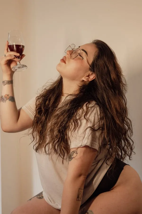 Woman Enjoying a Glass of Wine with a Confident Pose Indoors