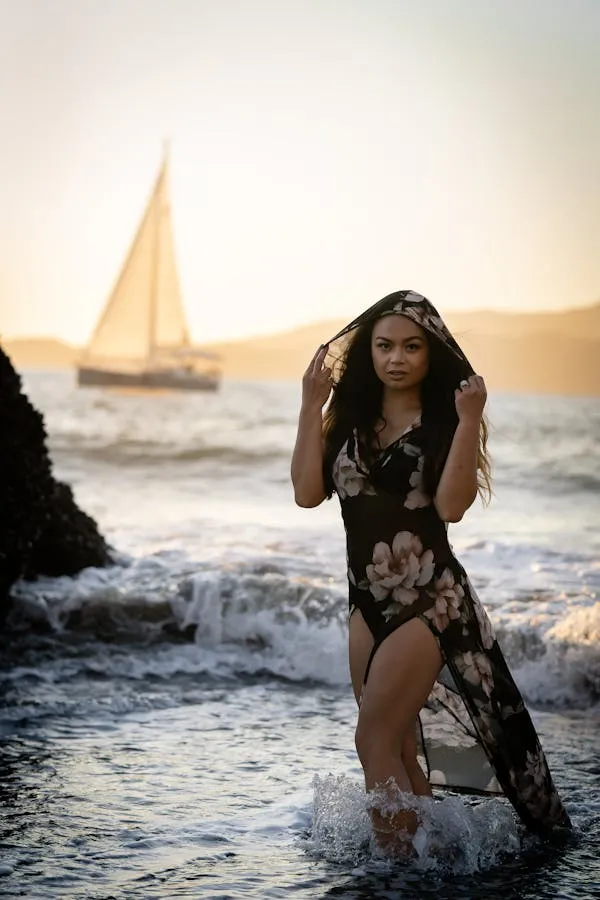 Woman Enjoying the Beach Breeze Near a Sailboat Wallpaper