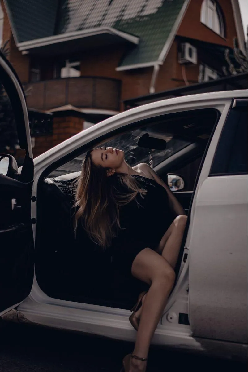 Woman Exiting a Car Wearing a Black Outfit in a Dynamic Pose