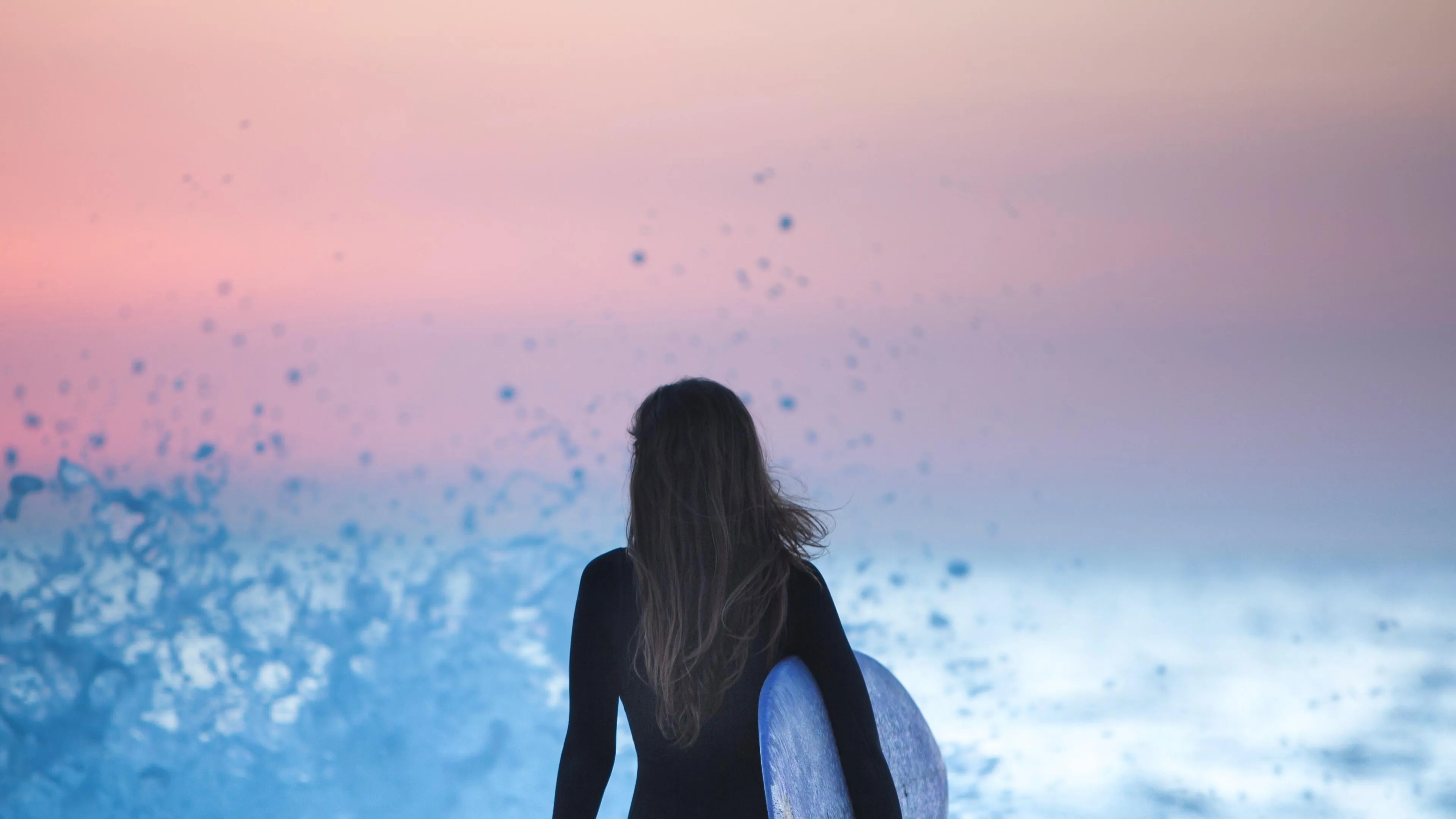 Woman Facing the Ocean Under a Pink and Blue Sunset Image