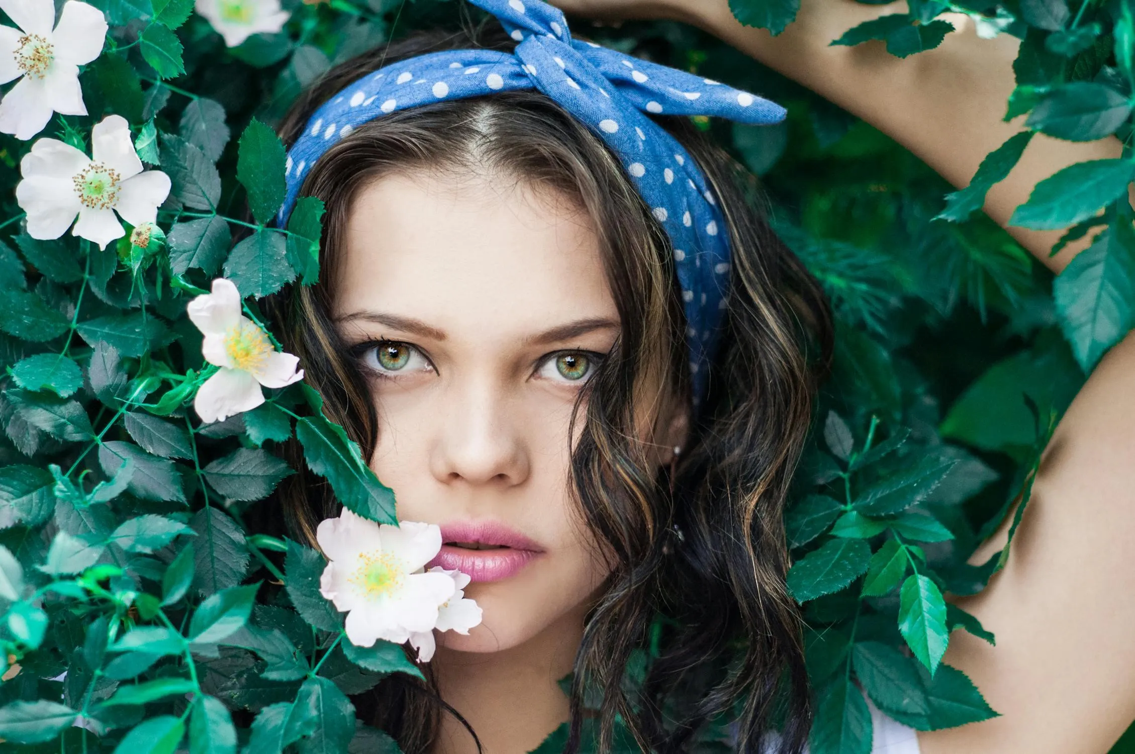 Woman with a Floral Headband Surrounded by Green Leaves