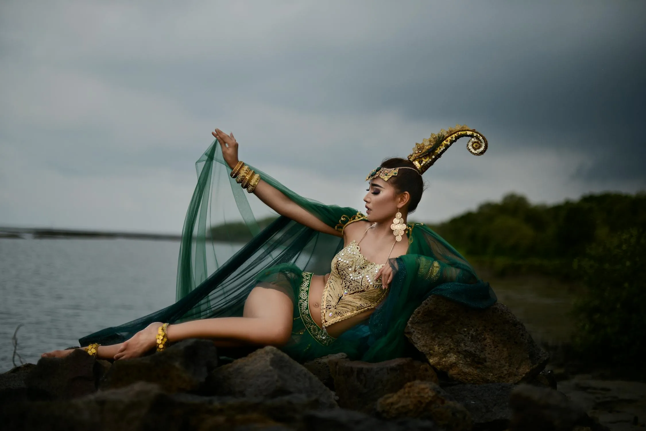 Woman in a Green Dress Posing Gracefully Near a Rocky Ocean