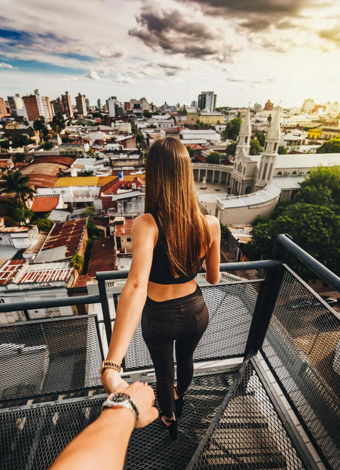 Woman Holding Her Partner Hand Overlooking the City Rooftop