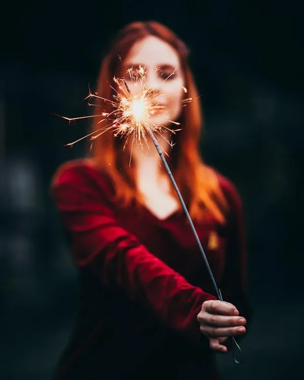 Woman Holding a Sparkler Glowing in the Night Free Wallpaper