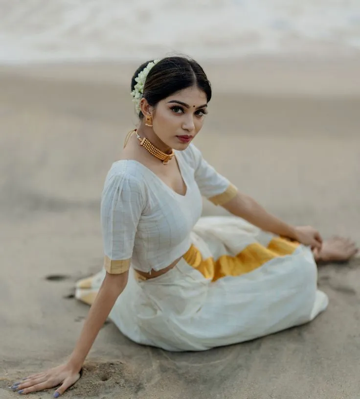 Woman in a Kerala white dress sitting on the sandy beach