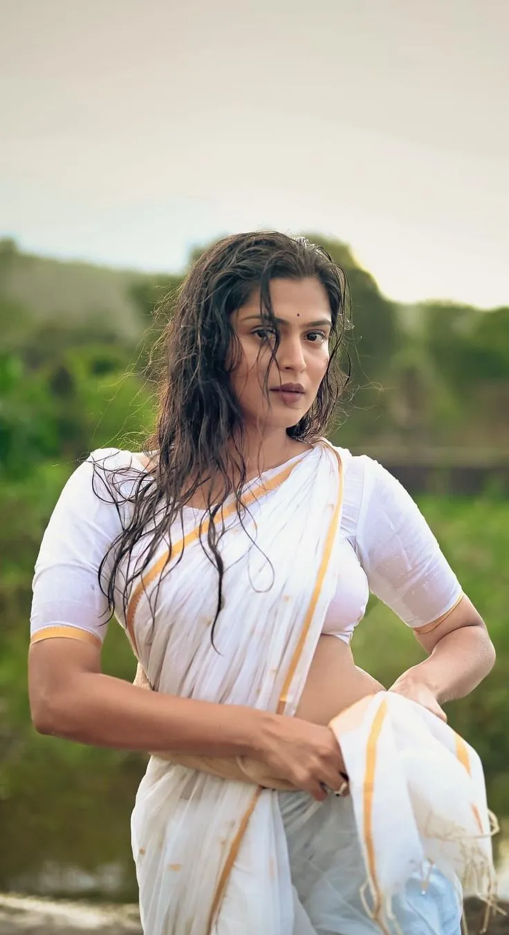 woman in a wet white saree standing near the water wallpaper