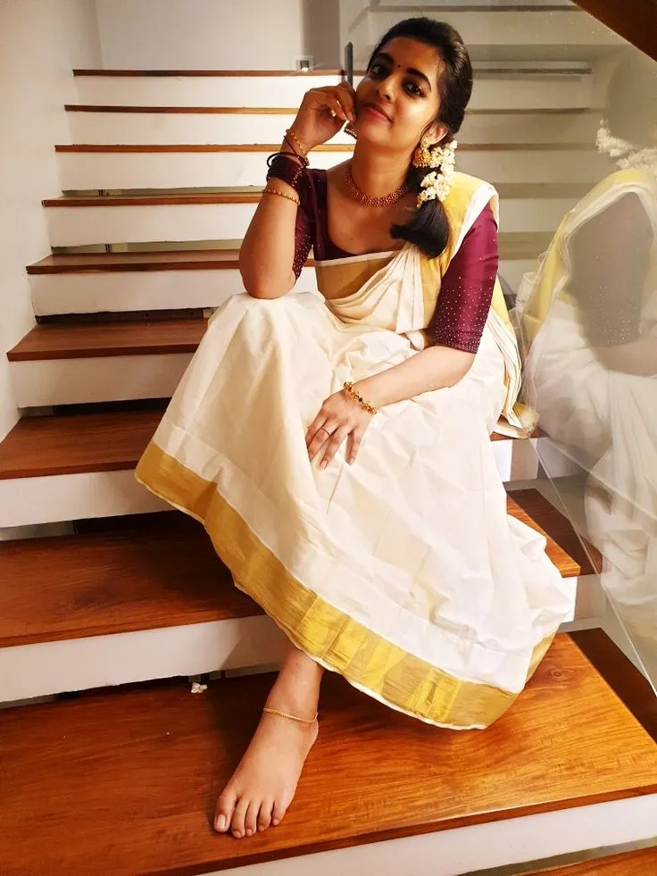 woman in a white nerial saree sitting in the strains image