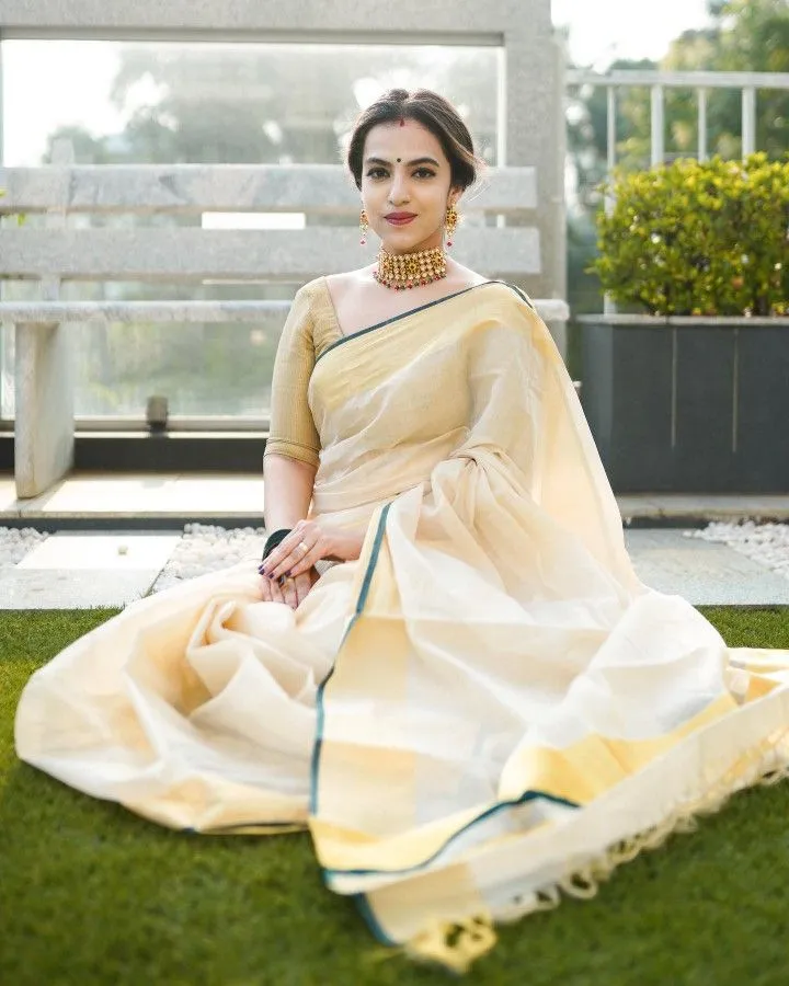 Woman in a white saree sitting on the grassy field wallpaper