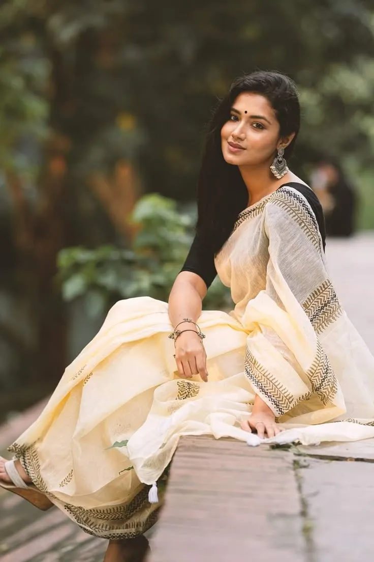 Woman in a white saree with a black blouse looking at camera