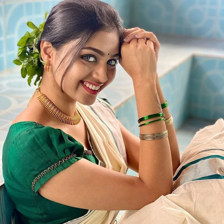 woman in a white saree with a green blouse looking at camera