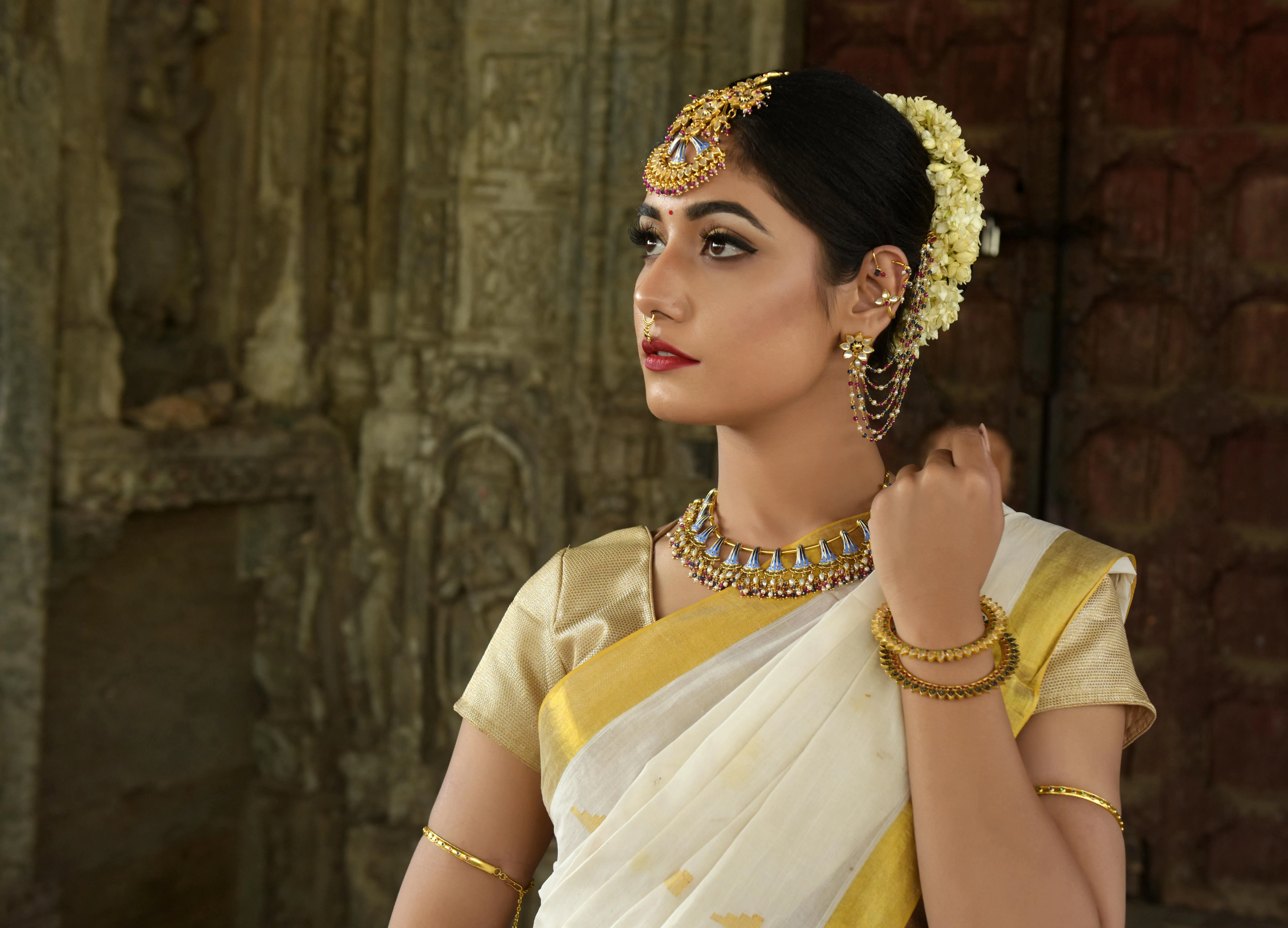 Woman in Cream Saree Wearing Gold Jewelry Posing Calmly