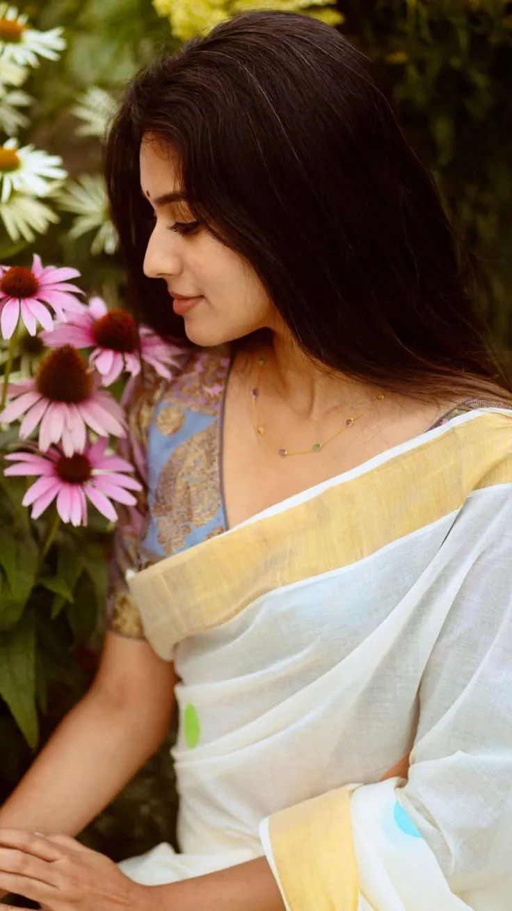 Woman in neriyal saree standing near pink and white flowers