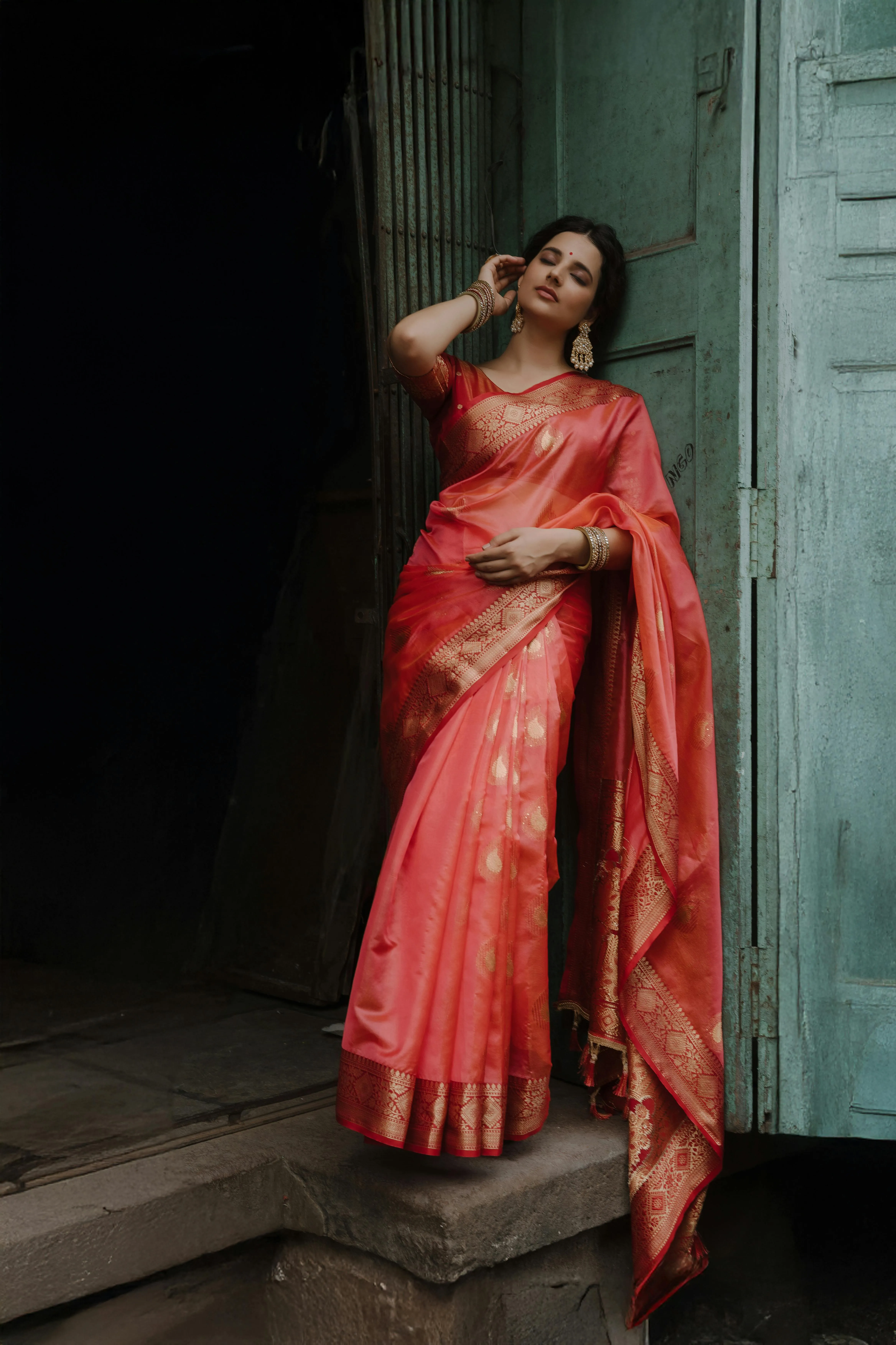 Woman in Pink Saree Standing at Doorway in Soft Light Image