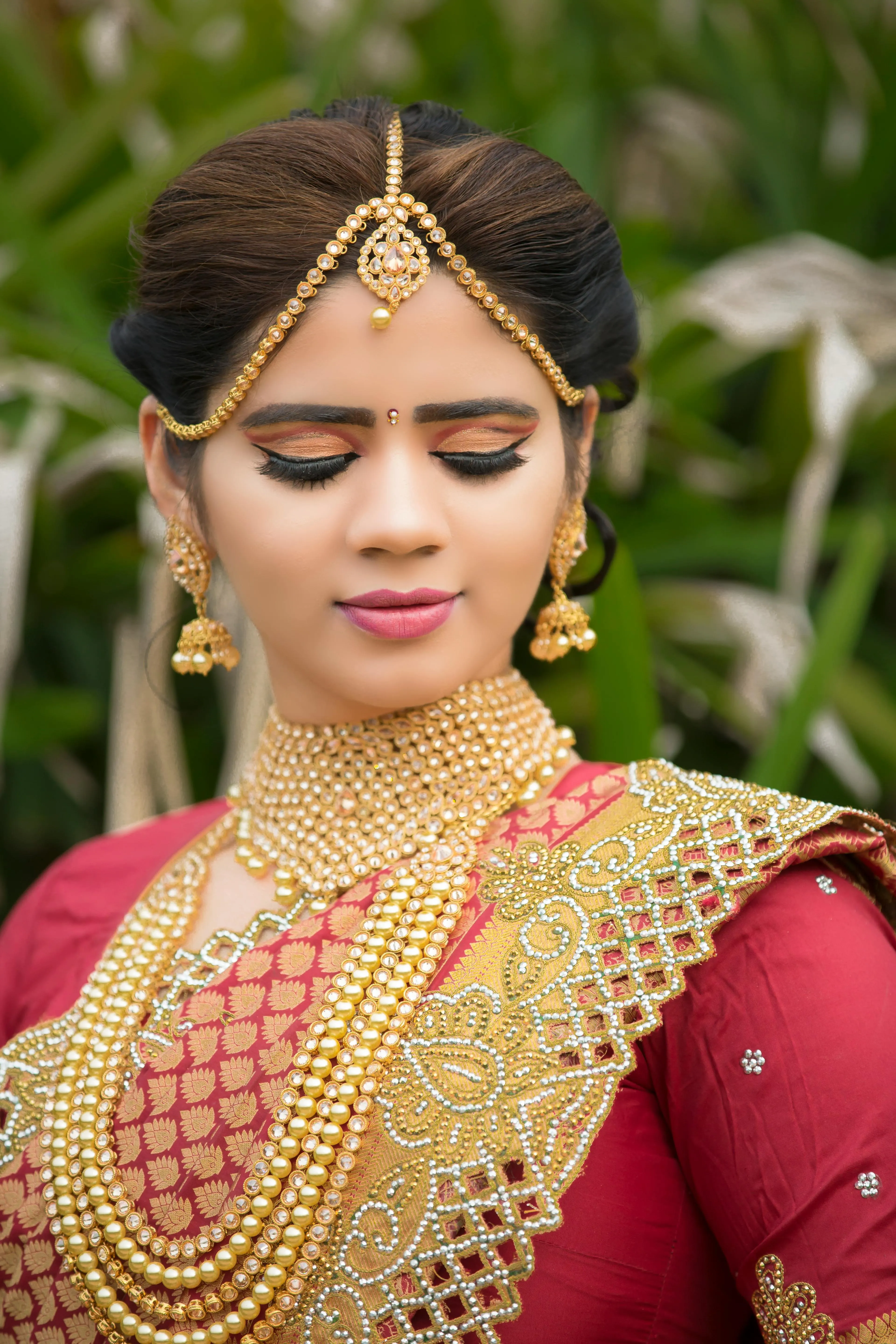 Woman in Red Saree with Heavy Gold Jewelry Looking Down