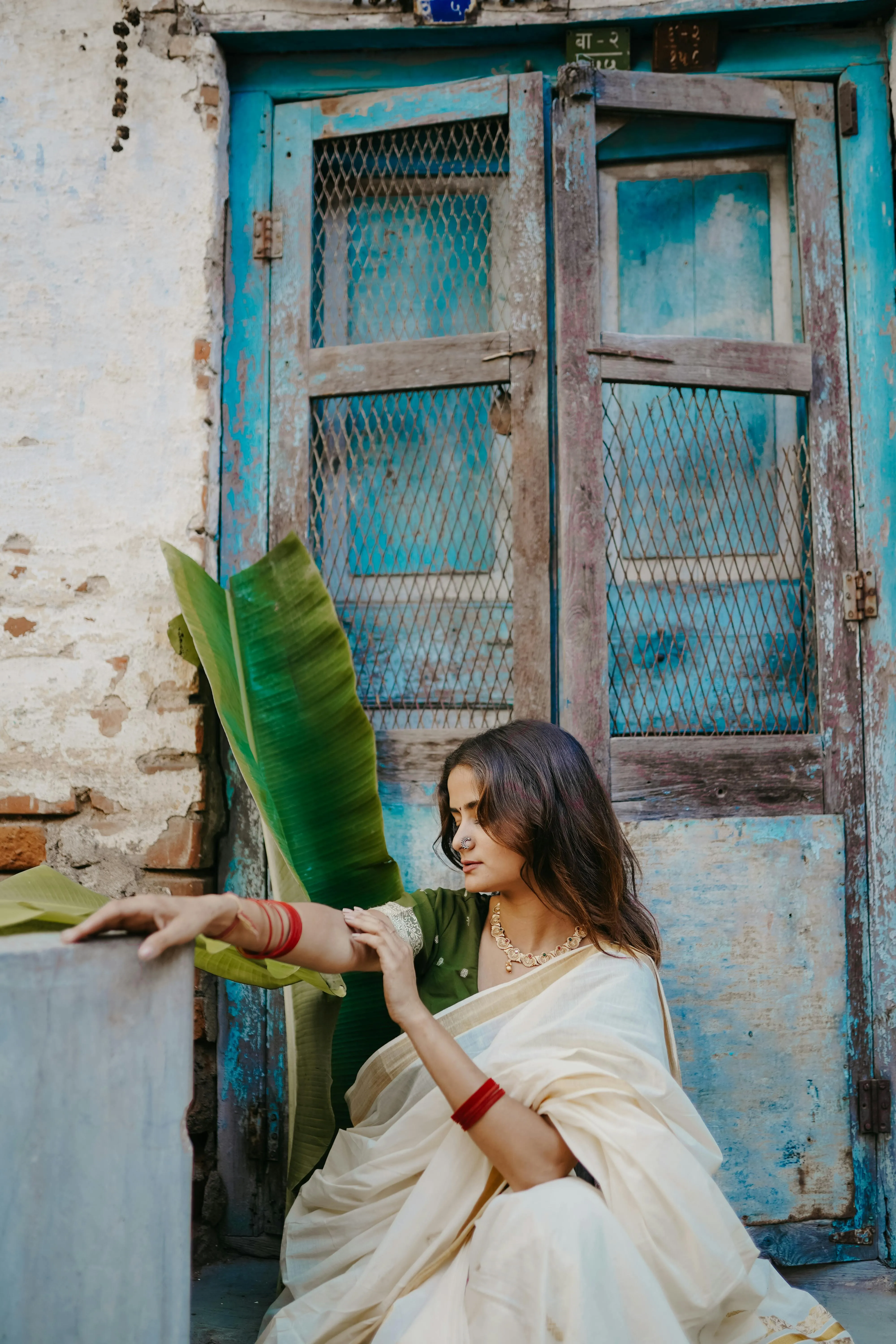 Woman in White Saree Sitting Near Blue Rustic Wooden Wall