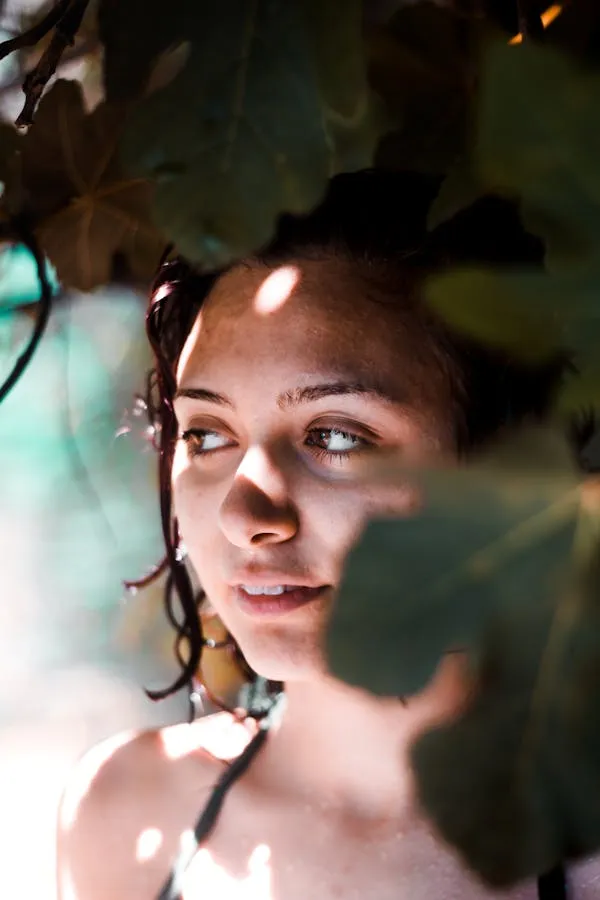 Woman Is Peeking Through Leaves with Sunlight on Her Face