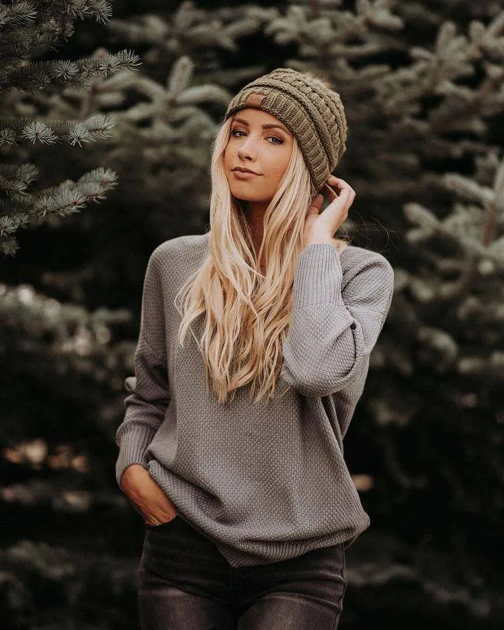 Woman in a Knitted Hat and Sweater Posing in a Winter Forest
