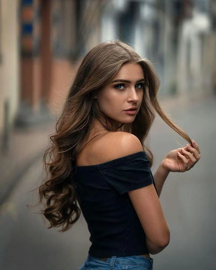 Woman with Long Hair Posing in a City Street Wearing a Dress