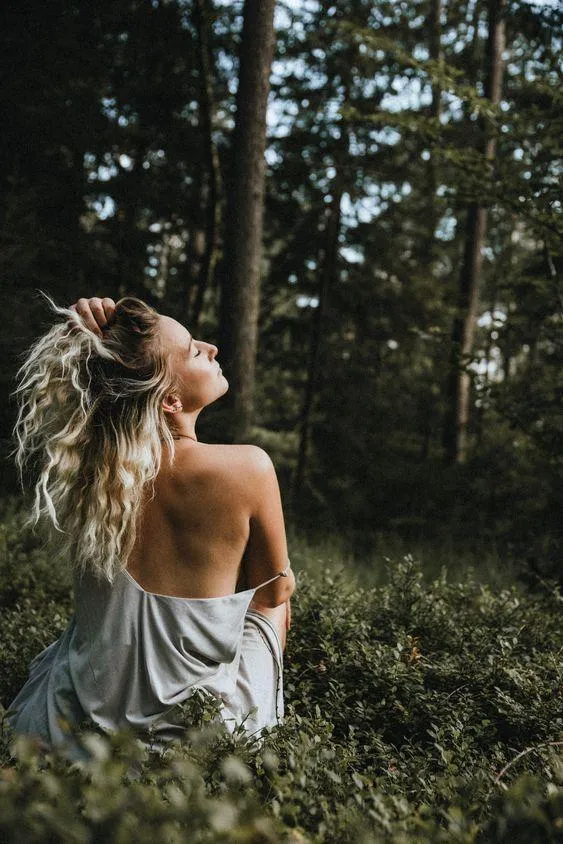 Woman with Long Hair Posing in Forest Wearing a White Dress