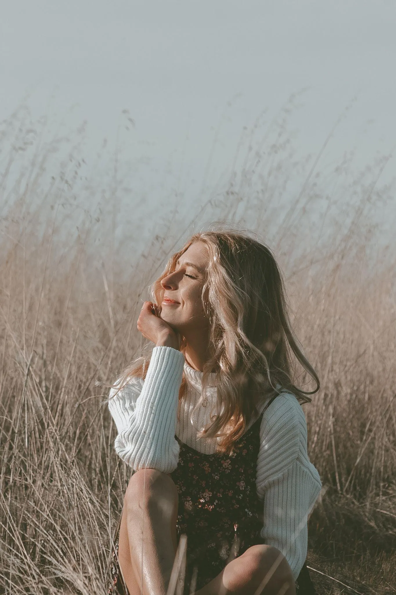 Woman Looking Up in an Open Field with Sunlight on Her Face