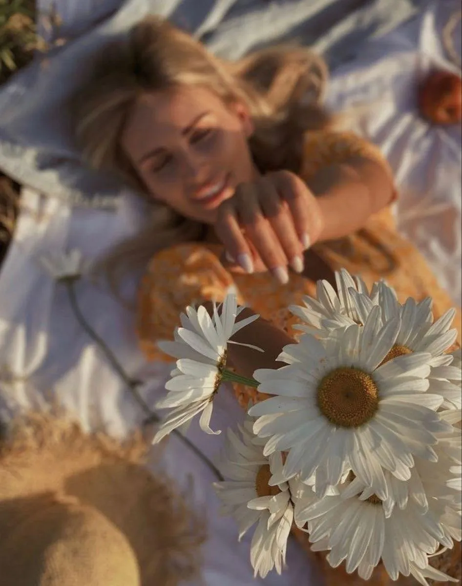 Woman Lying in a Bed Holding Flowers and Smiling Warmly