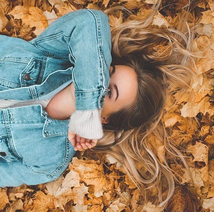 Woman Lying on Fallen Leaves Wearing Denim Jacket Wallpaper