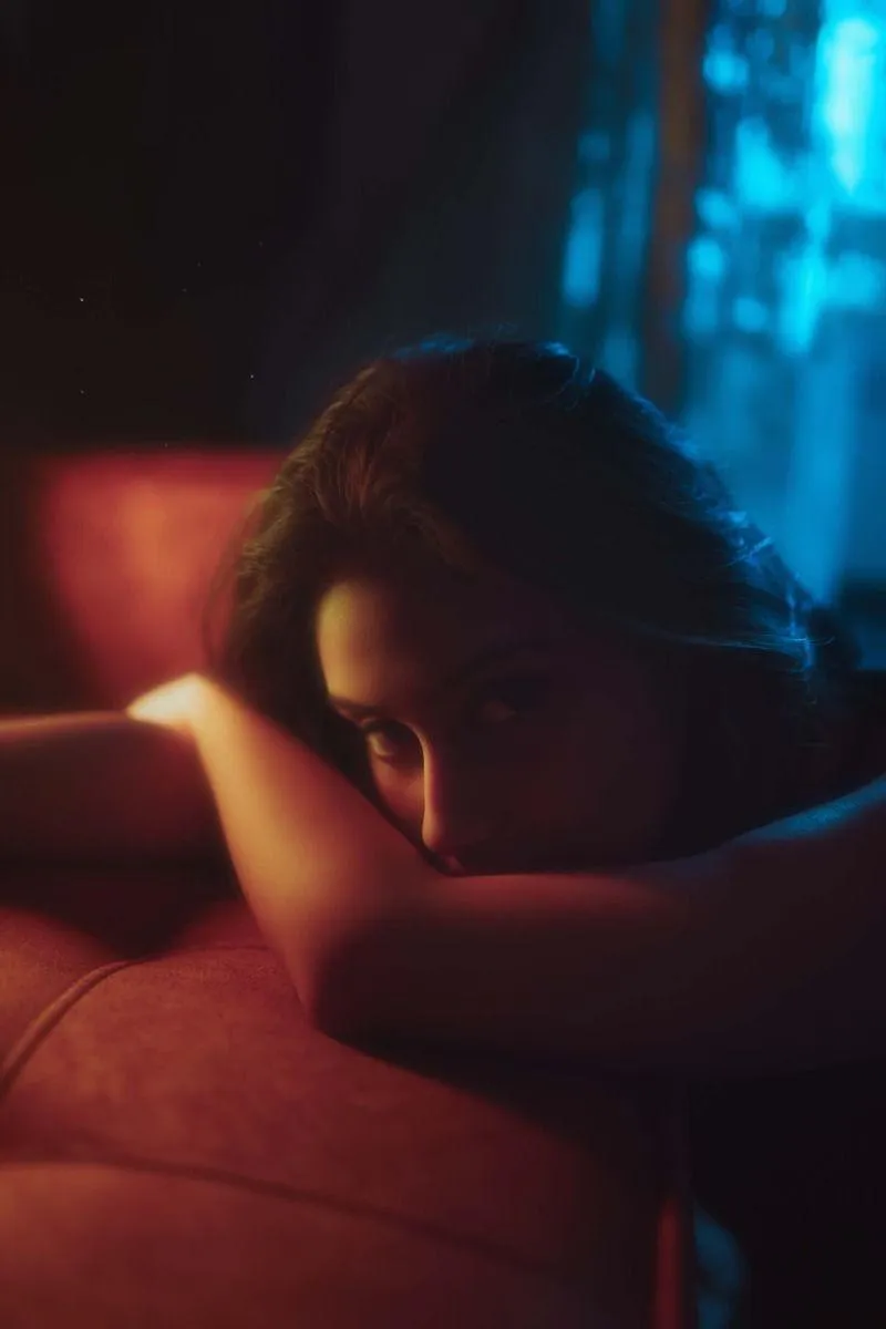 Woman Lying on a Red Couch in a Dimly Lit Moody Setting