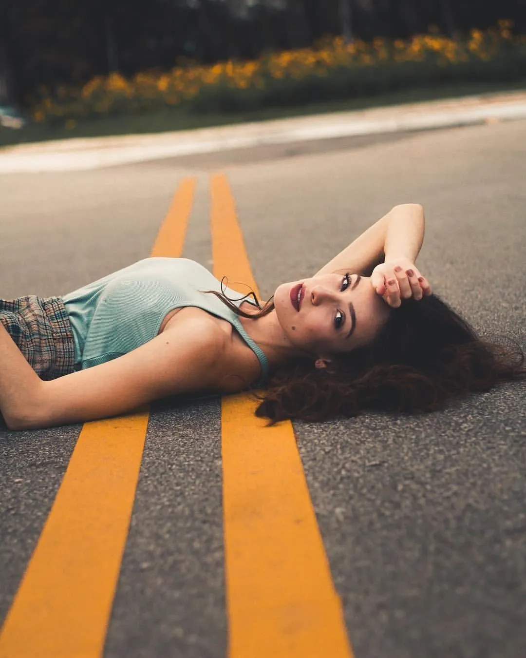 Woman Lying on the Road with Yellow Lines on the Asphalt