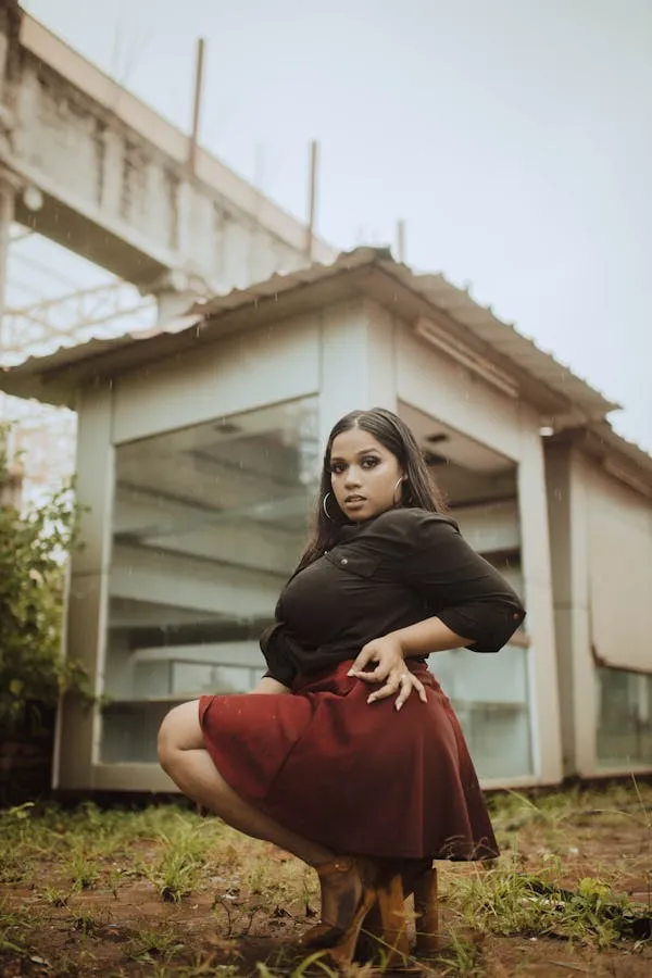 Woman in a Maroon Outfit Posing Near an Abandoned Building