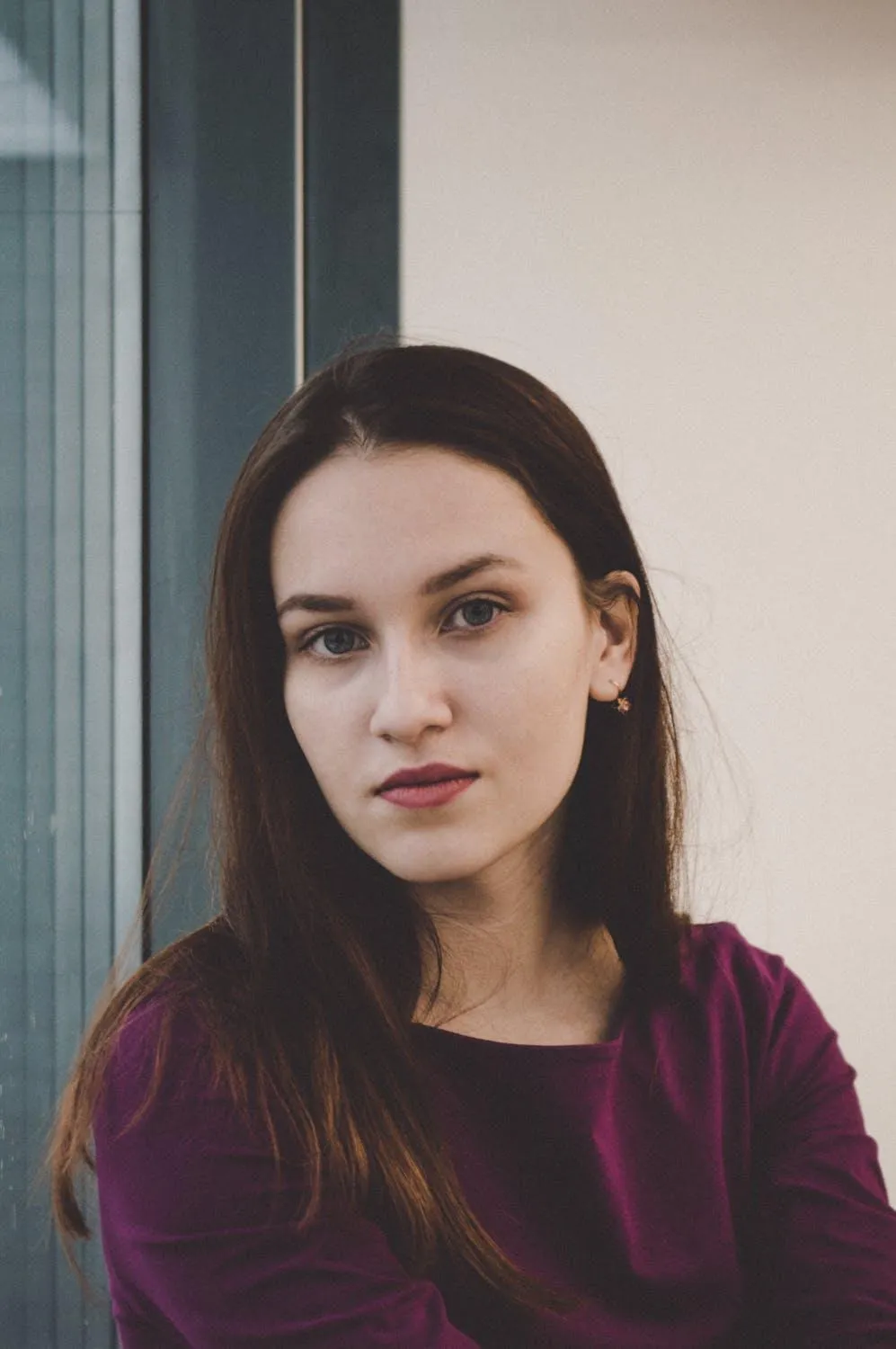 Woman with a Maroon Top Standing Indoors with a Calm Look