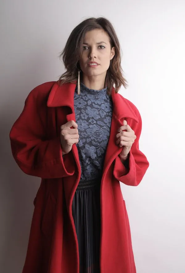 Woman Model in a Red Coat Posing Indoors with a Serious Gaze