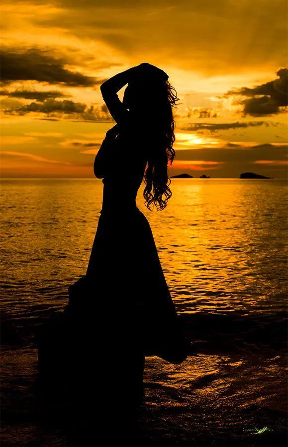 Woman Model Standing in Silhouette by the Ocean At Sunset