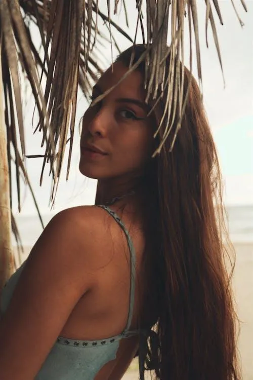 Woman Model Under Palm Leaves Looking Back with a Soft Gaze