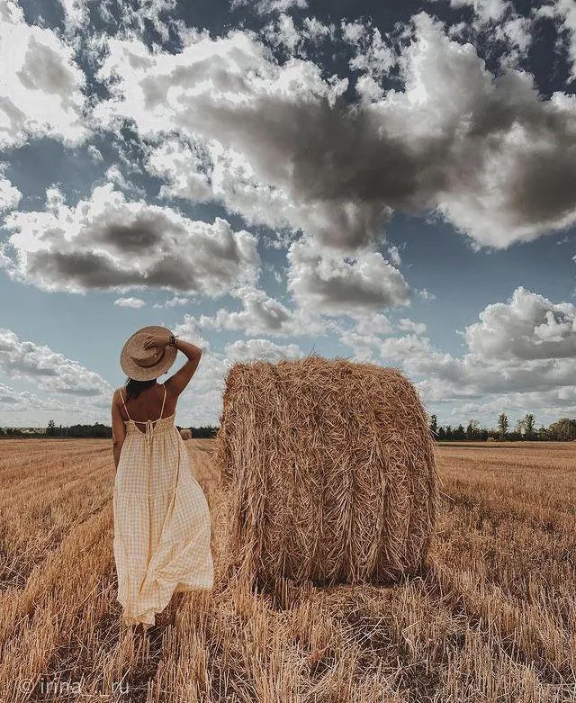 Woman Model Walking Near a Haystack Under a Cloudy Blue Sky