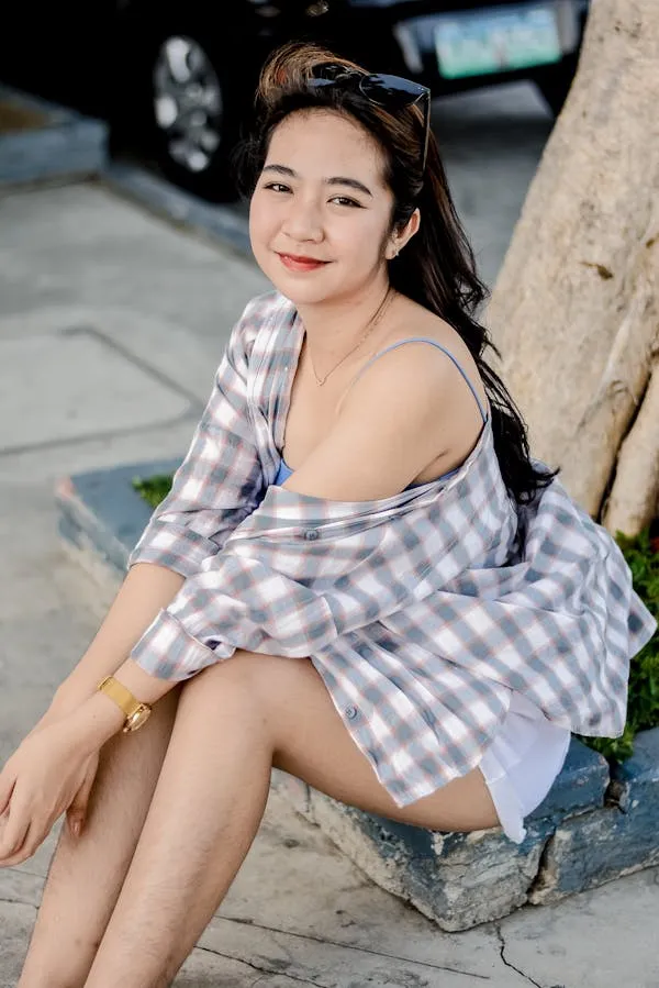 Woman in a Plaid Shirt Sitting Casually on a City Street