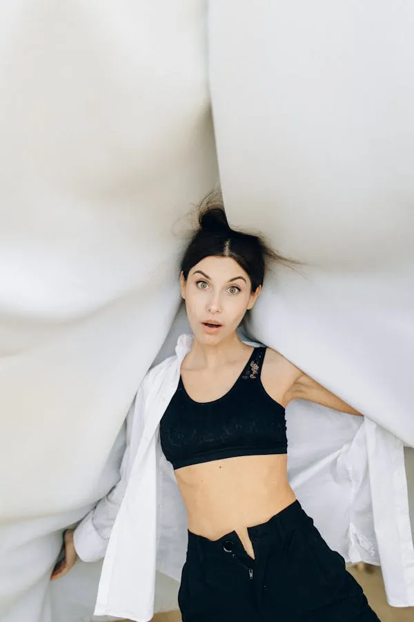 Woman Posing Between White Draped Fabric Wearing a Black Top