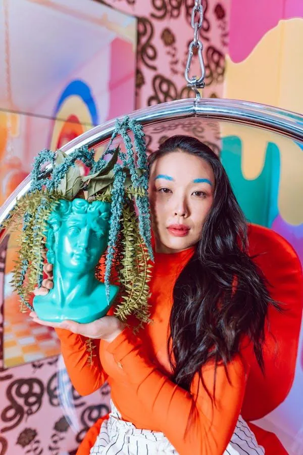 Woman Posing with Blue Statue Head in Vibrant Art Setting
