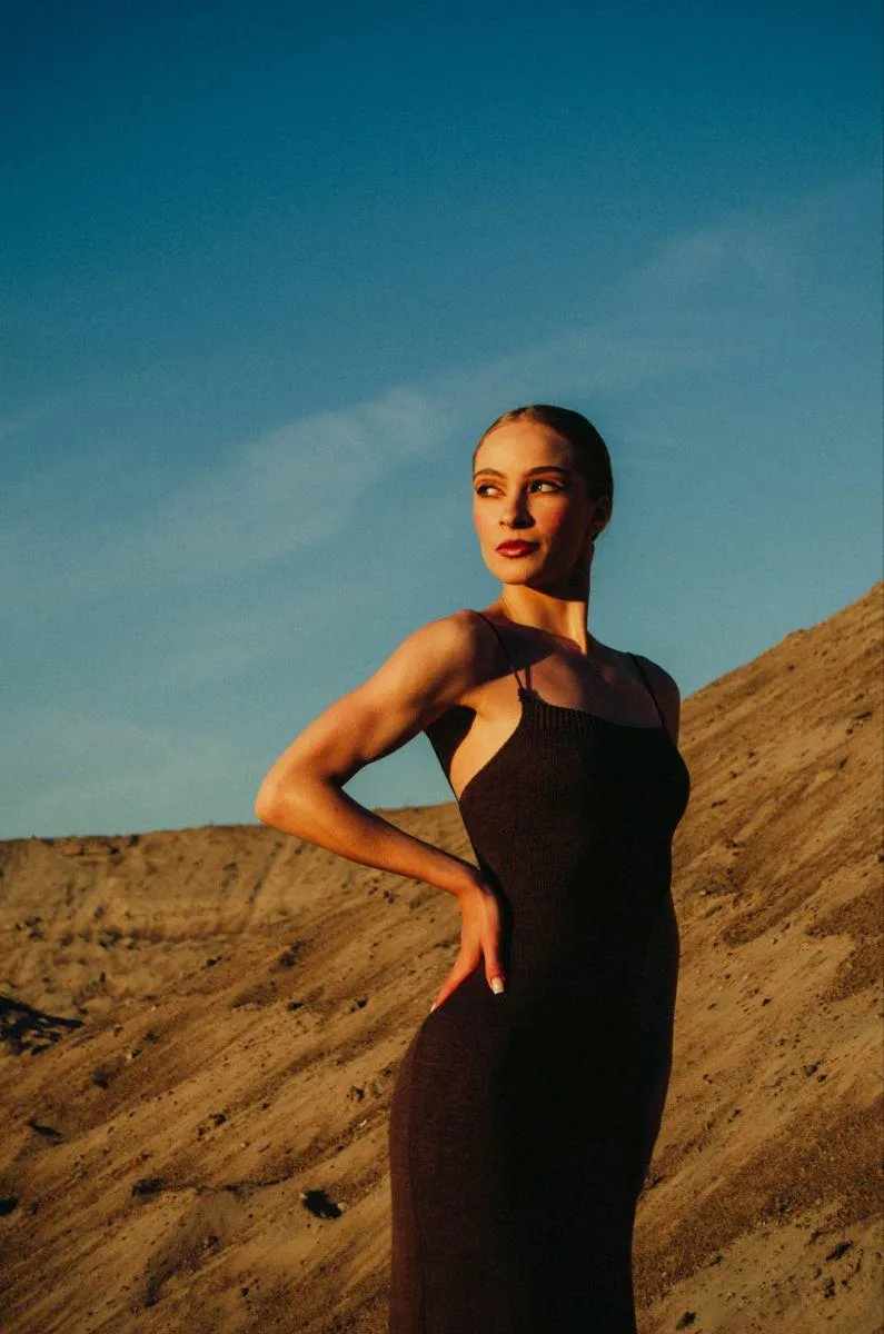Woman Posing Confidently in a Black Dress on a Rocky Cliff