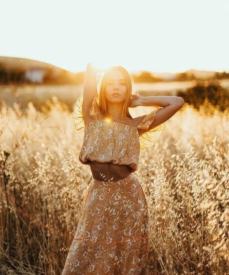 Woman Posing in a Field Wearing a Floral Dress At Sunset
