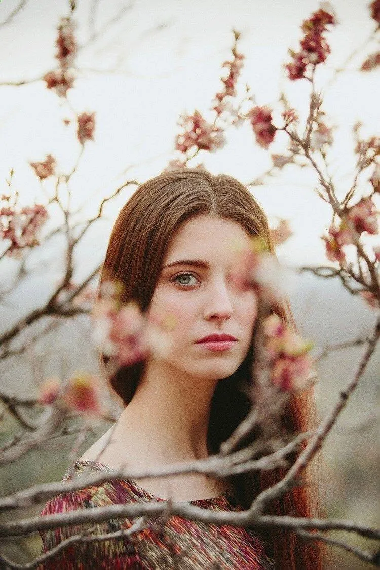 Woman Posing Near Spring Blossoms with a Soft Expression