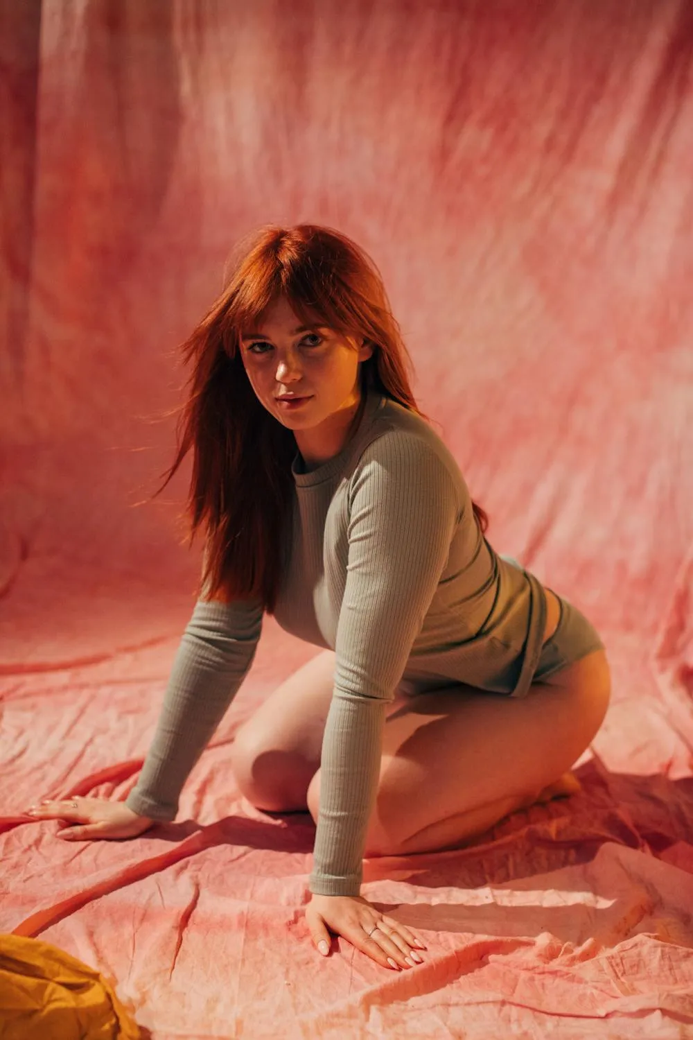 Woman Posing on the Floor with Pink Lighting and Soft Fabric