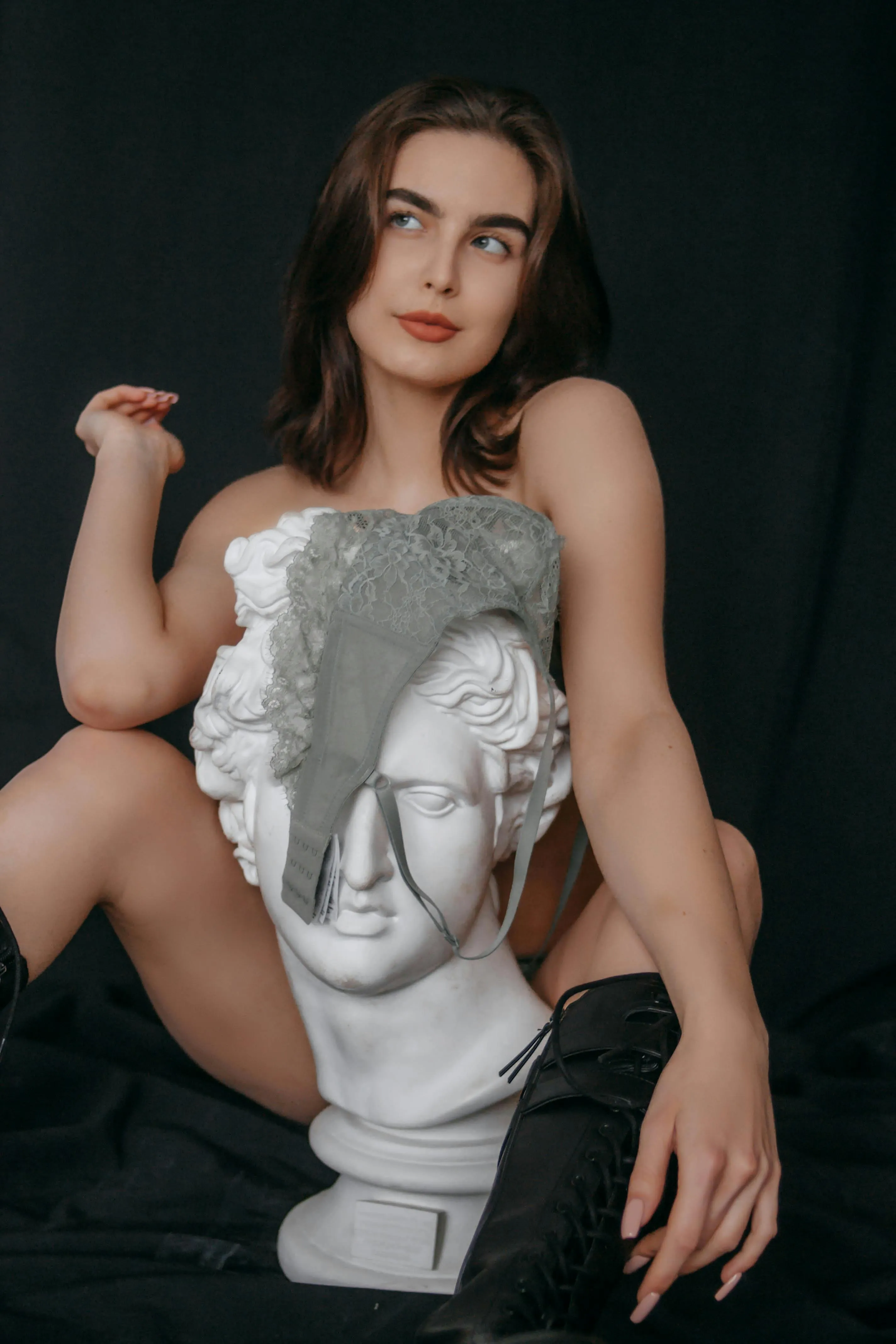 Woman Posing with White Sculpture Against a Black Background