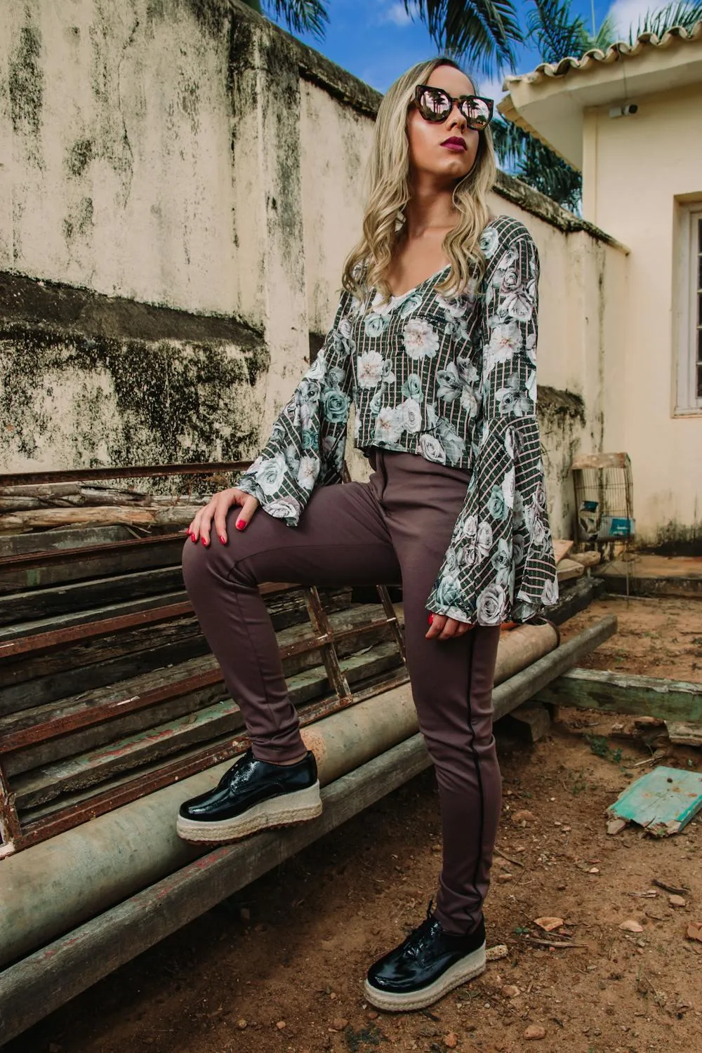 Woman in a Printed Shirt Standing on Pipes Near Old Building