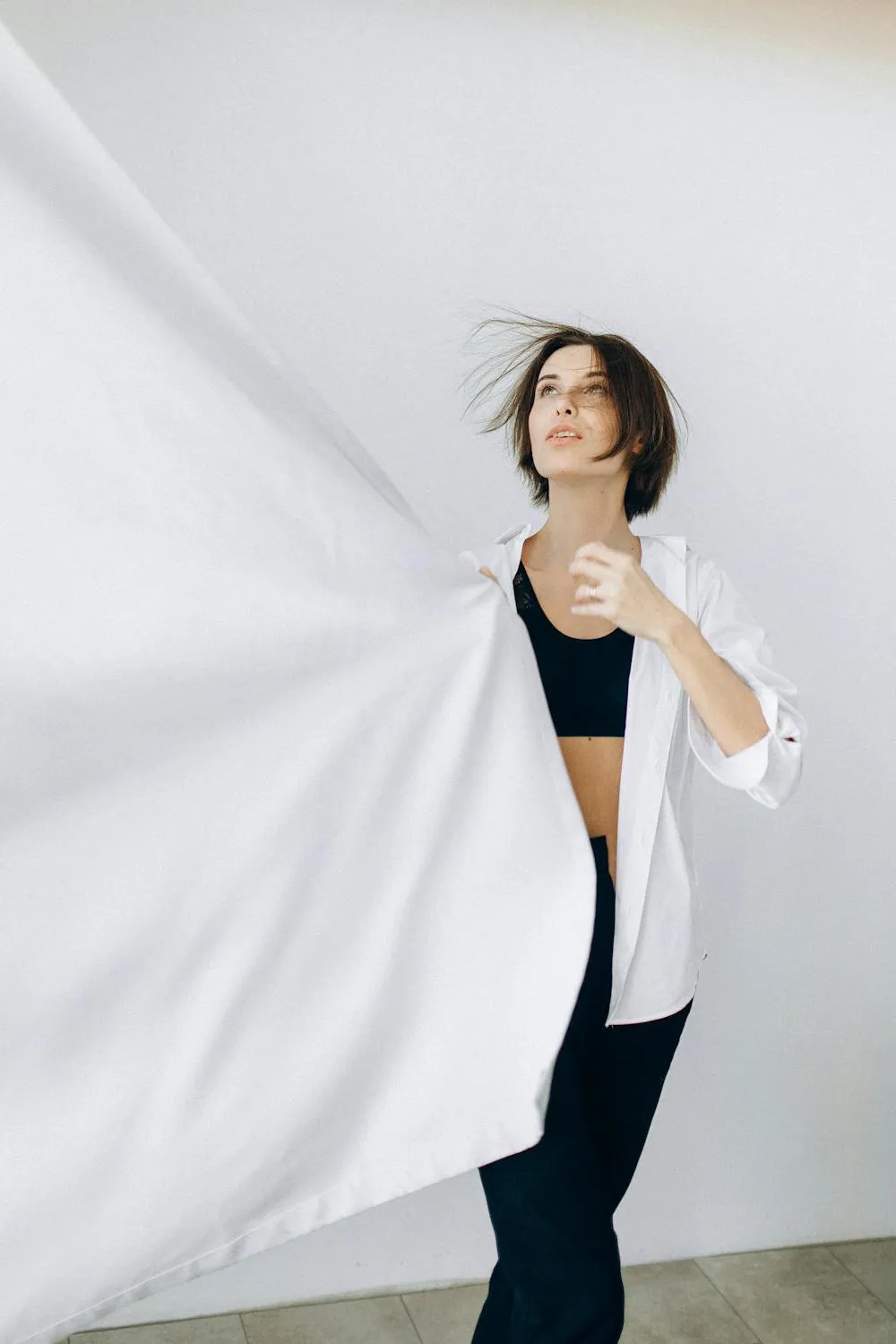 Woman Pulling White Fabric To the Side in Minimalistic Room